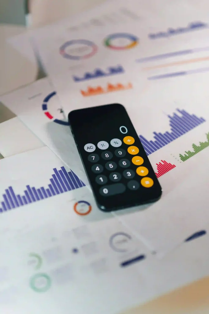 A calculator and smartphone on a desk surrounded by financial documents, illustrating modern business finance management.